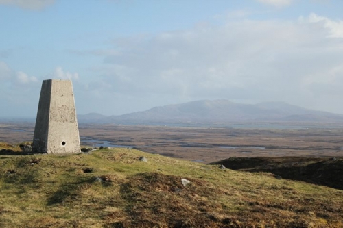 The triangulation point at the summit of Rueval, looking towards South Uist. The district of Carnan is in view, with Hecla and Beinn Mhor in the background. Beinn Mhor is classed as a Graham, that is, a hill between 2000 to 2500 ft.