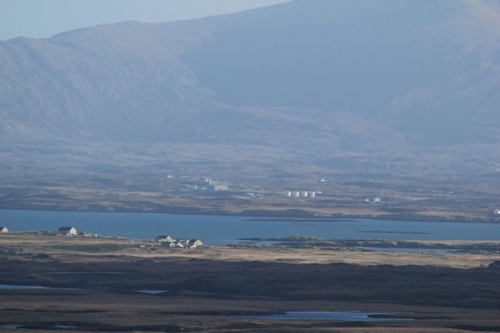 From the summit of Rueval. Lochcarnan looks close. Taken with a telephoto lens at full tilt. The storage tanks of Lochcarnan pier can be seen clearly.